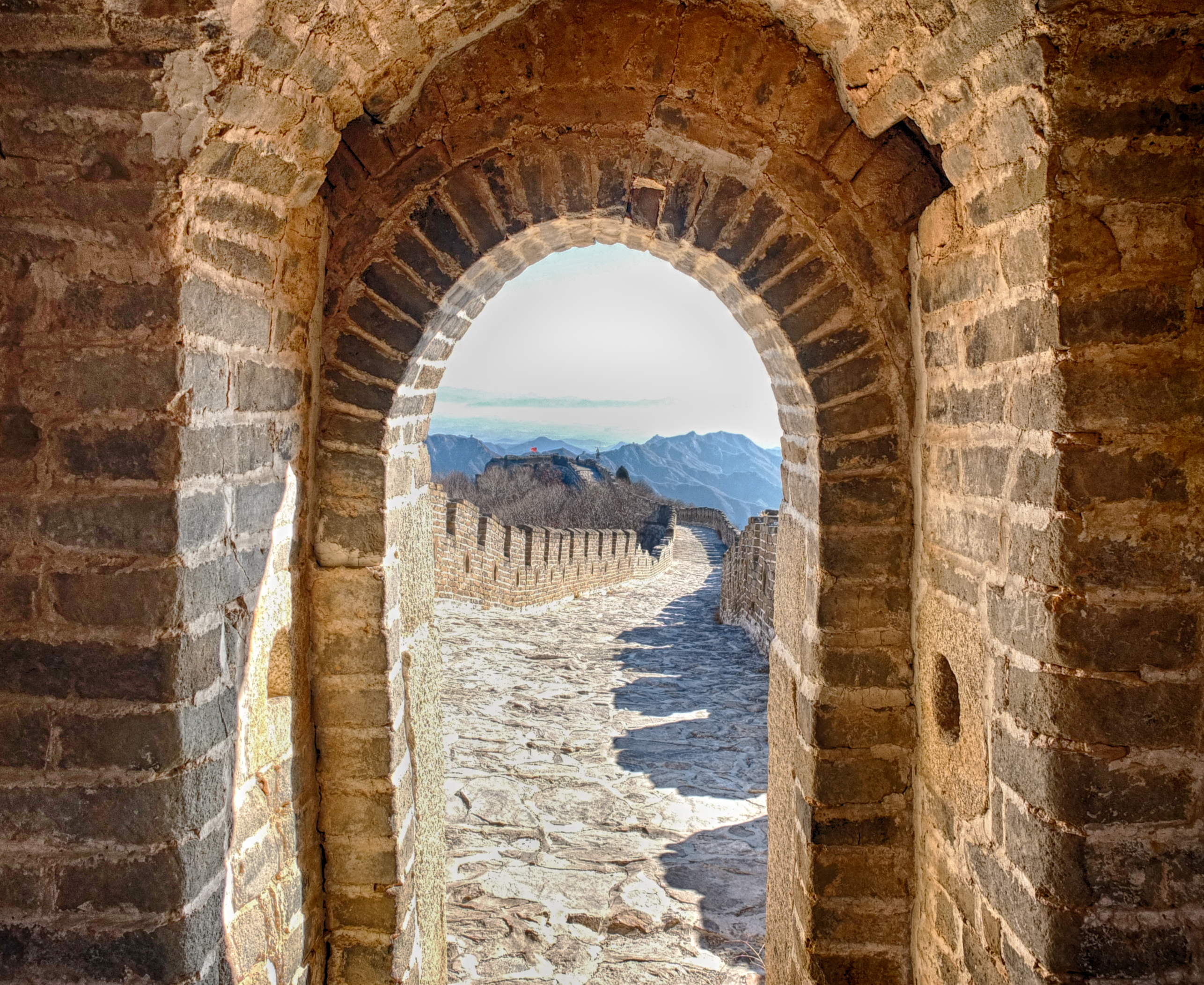 a stone archway with a mountain range in the background