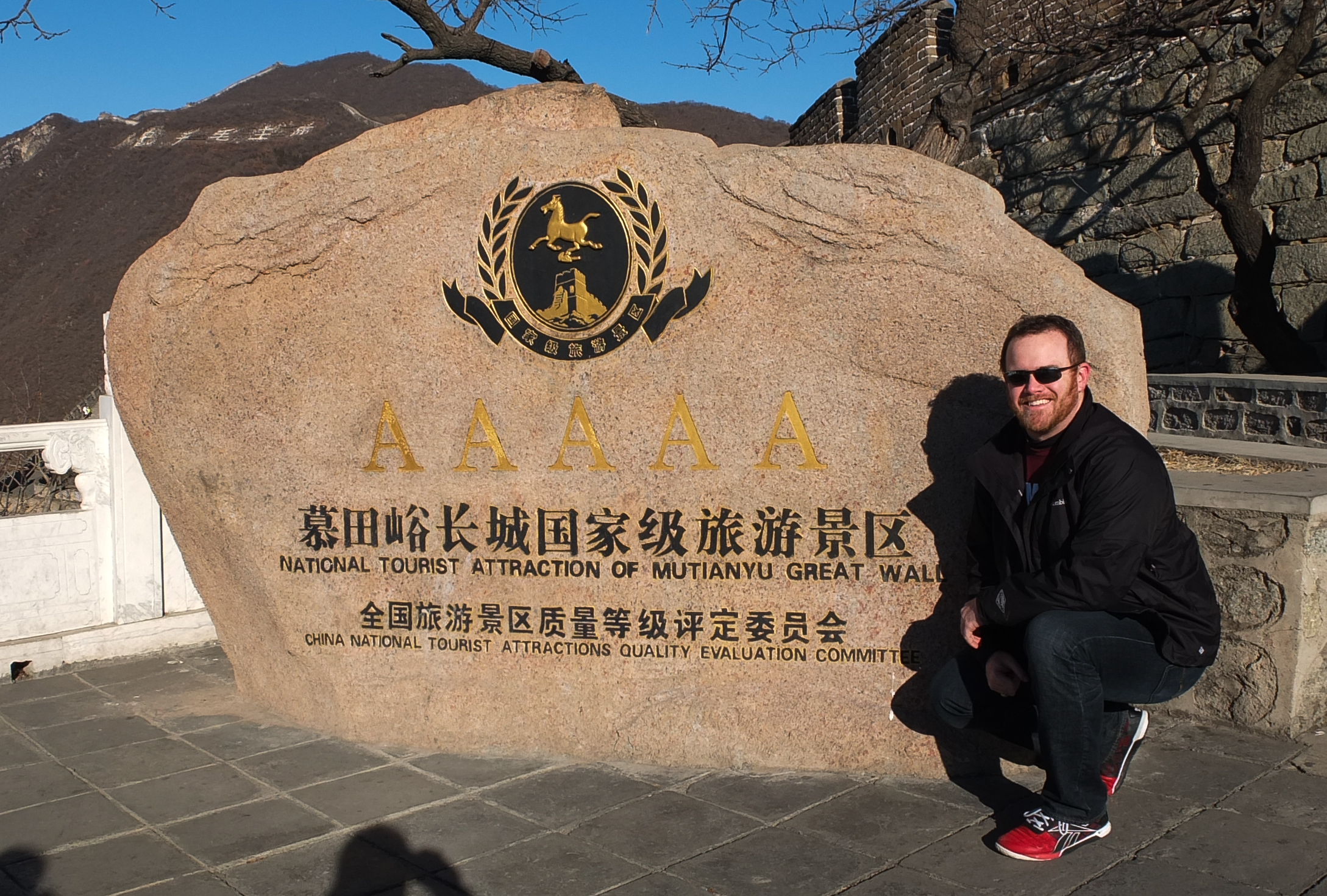 a man posing in front of a large stone sign