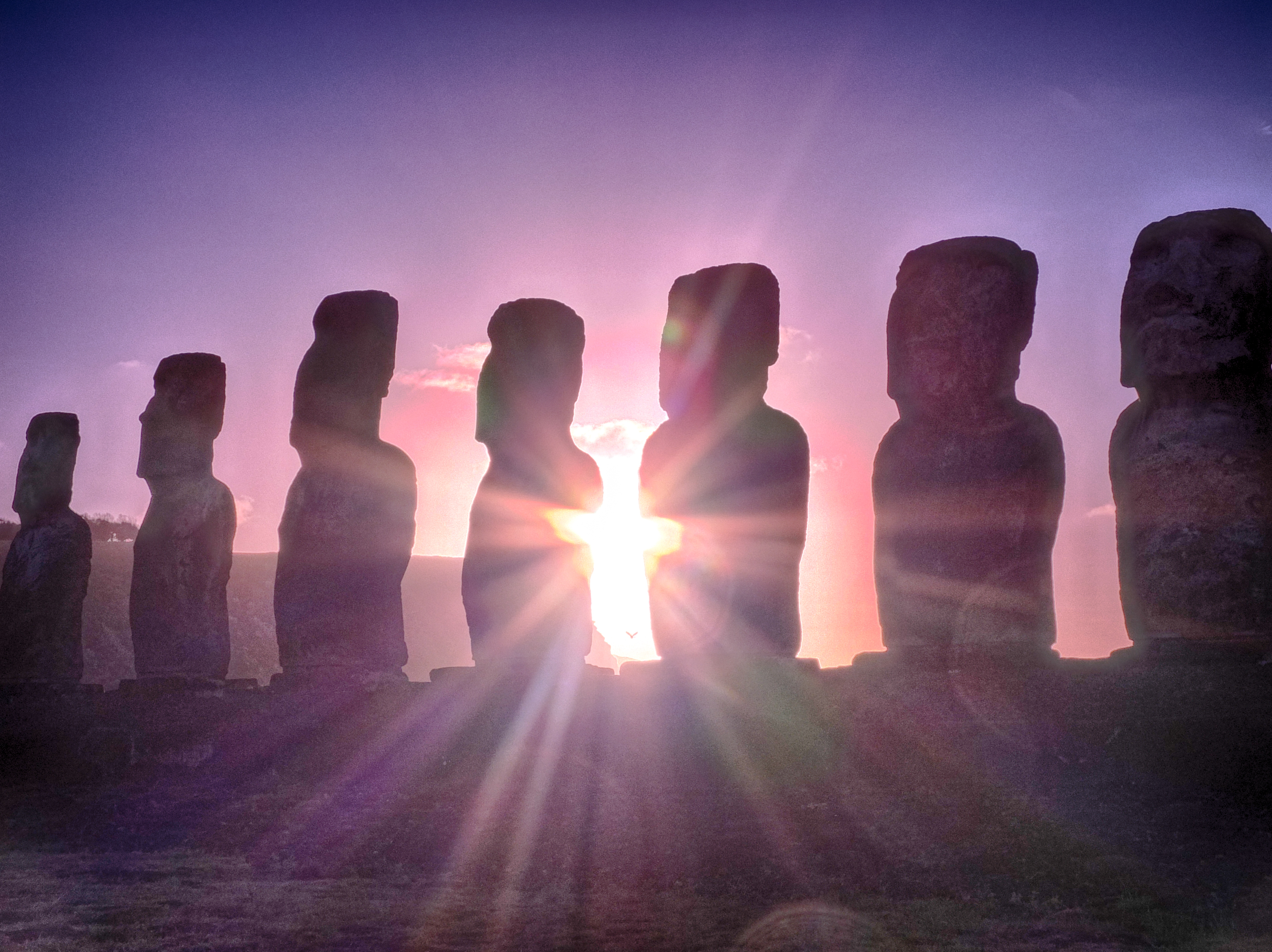a group of statues with the sun shining through them