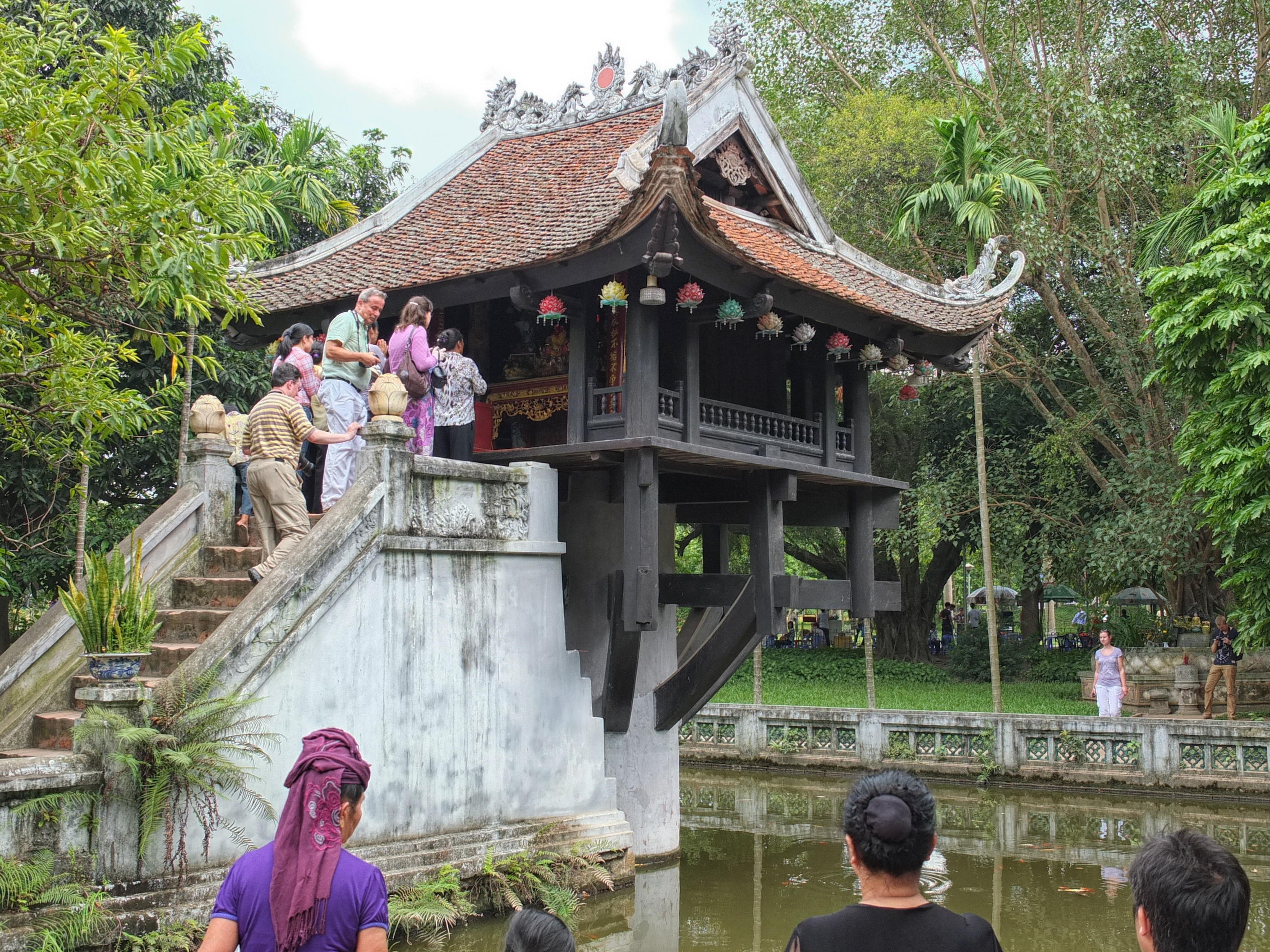 a group of people standing on a staircase next to a pond
