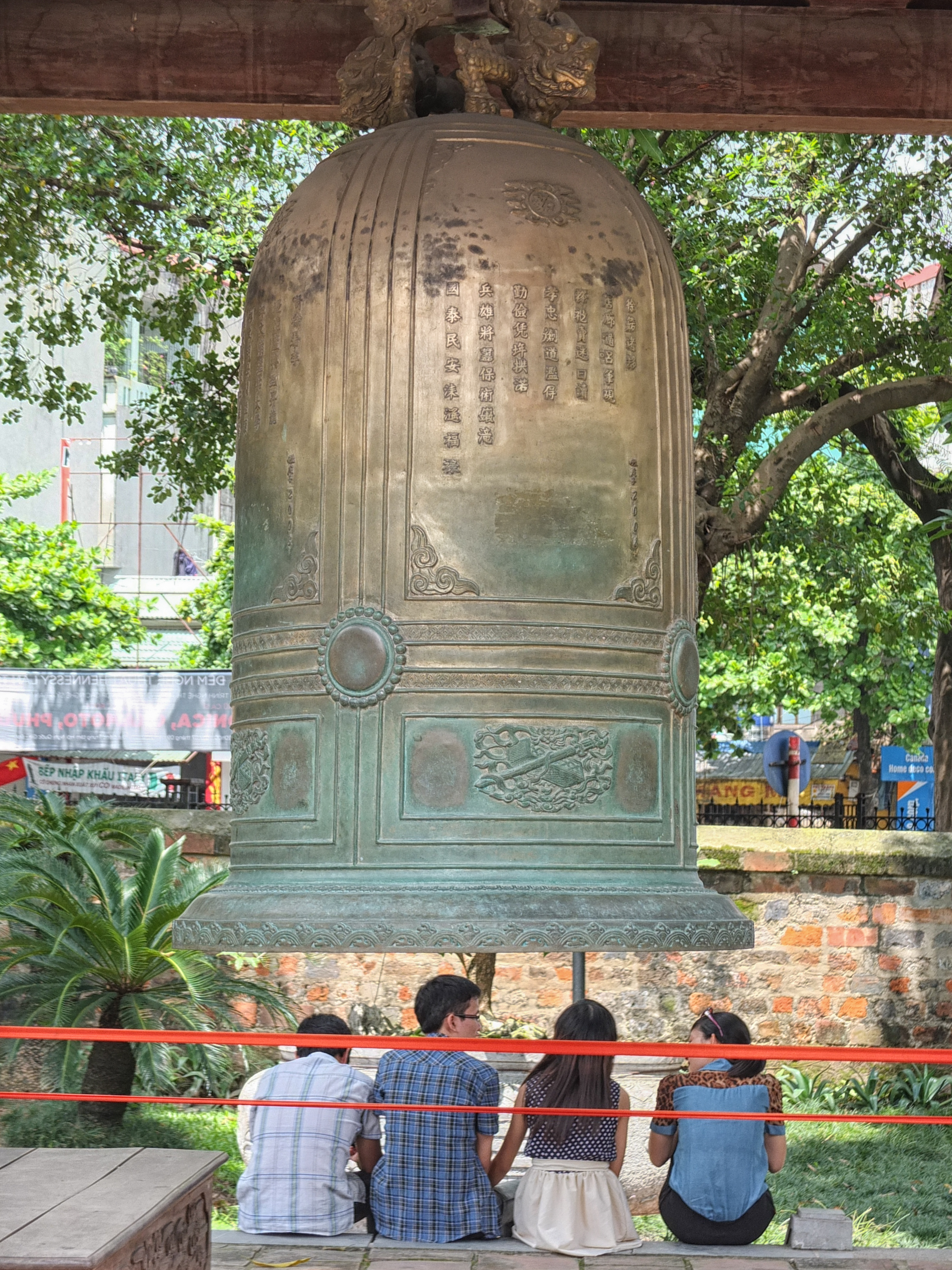 a group of people standing under a large bell
