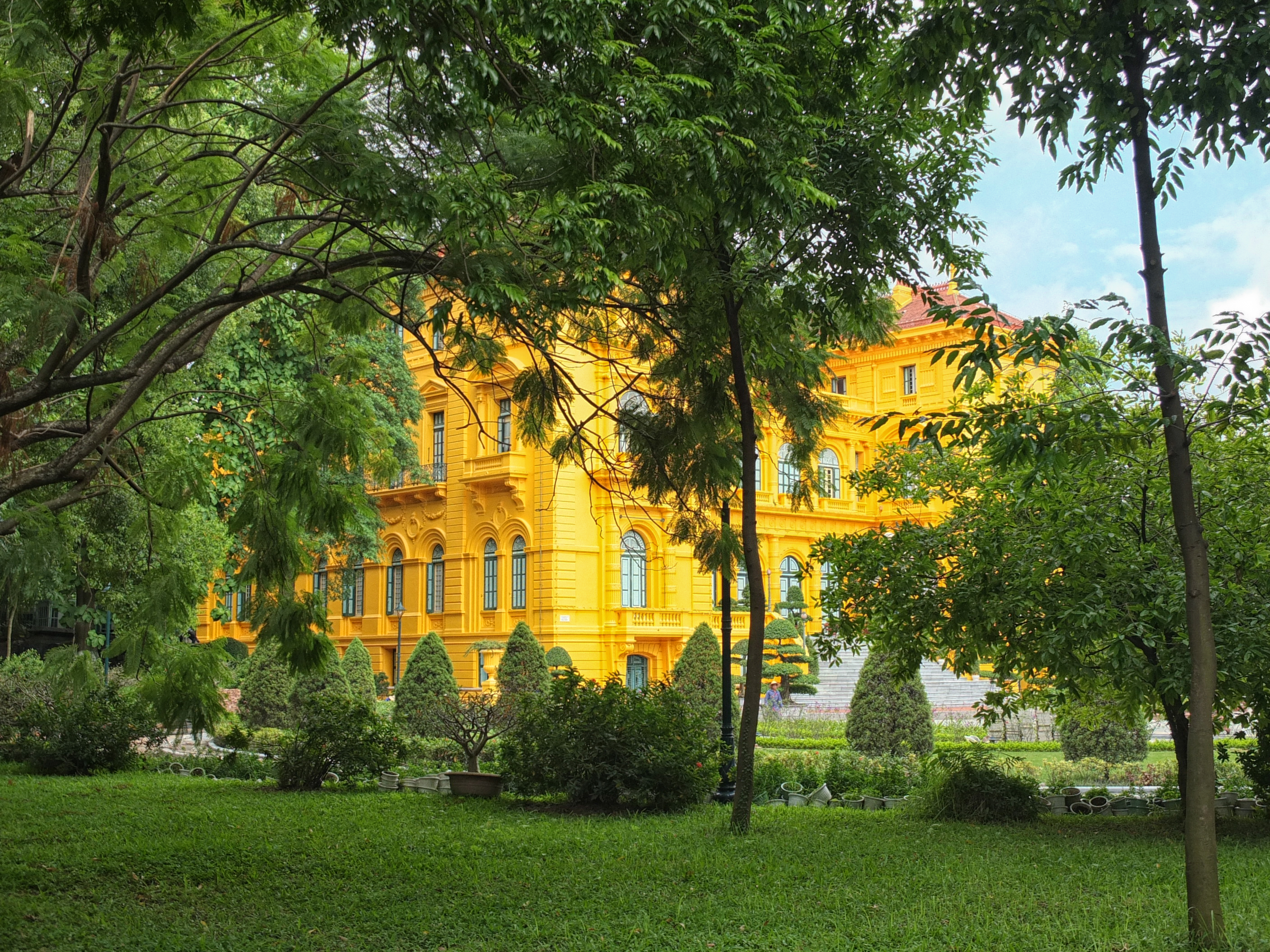 a large yellow building with trees in front