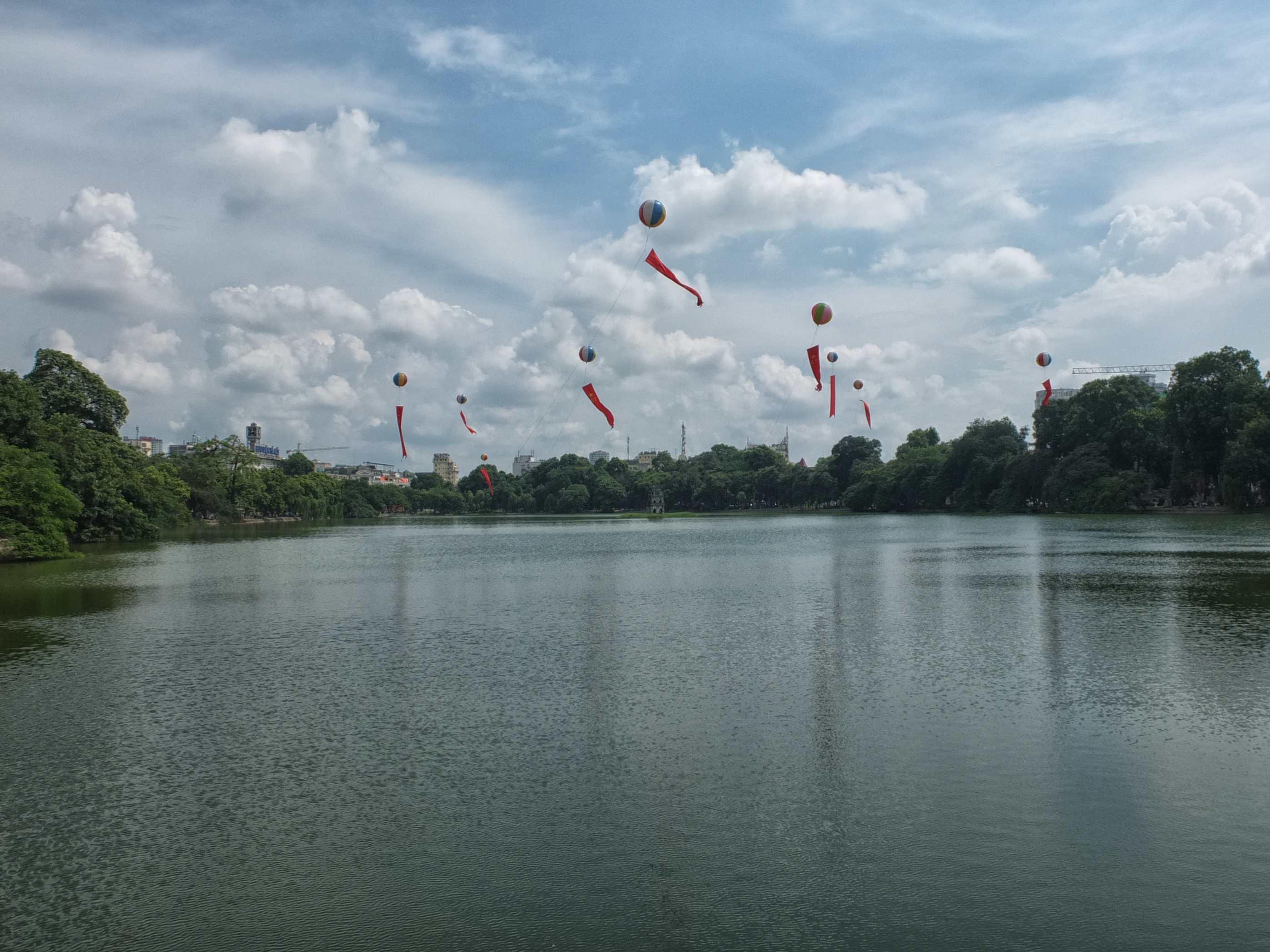 a group of balloons flying over a lake