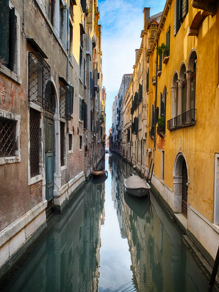 a narrow canal between buildings with boats