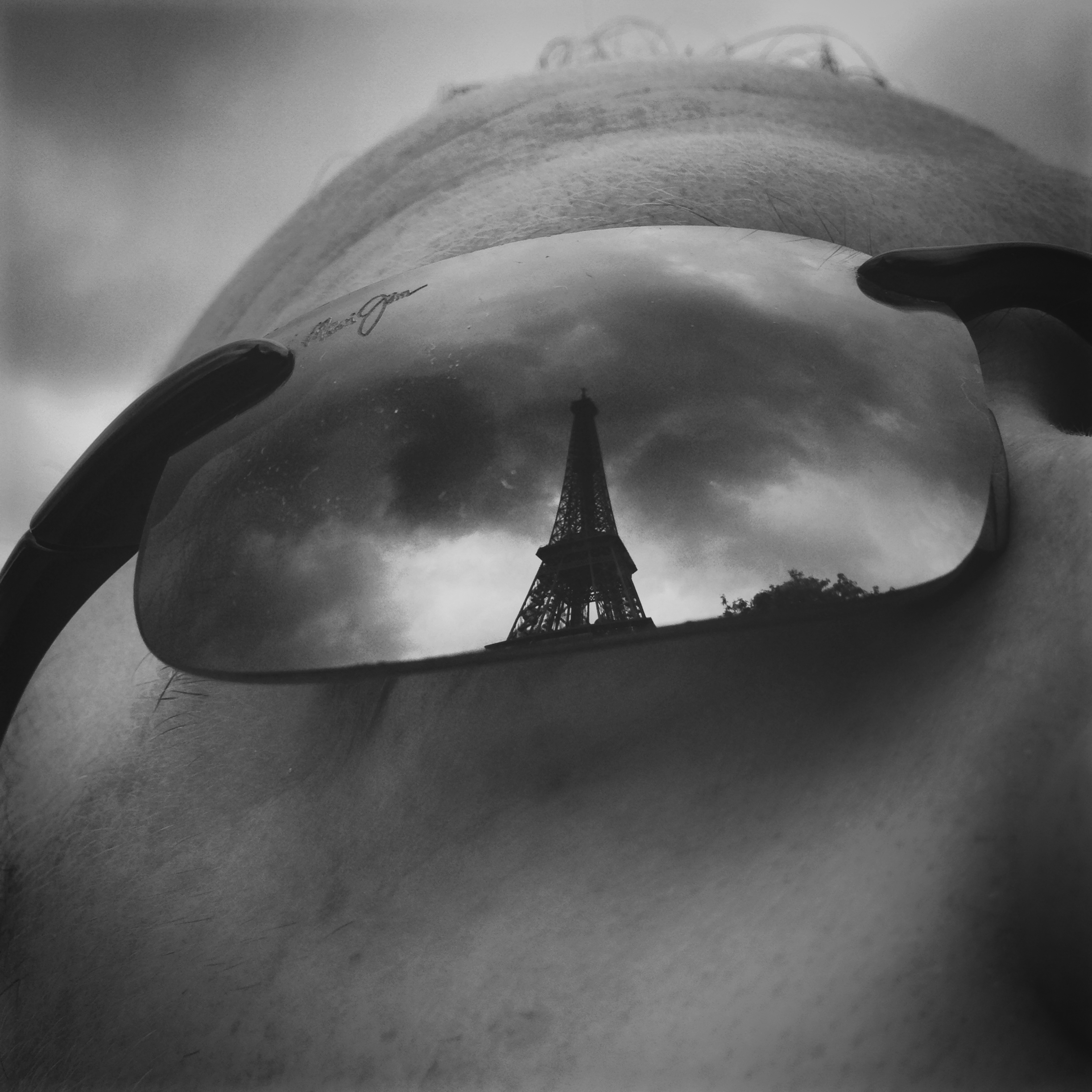 a person's face with sunglasses reflecting the eiffel tower
