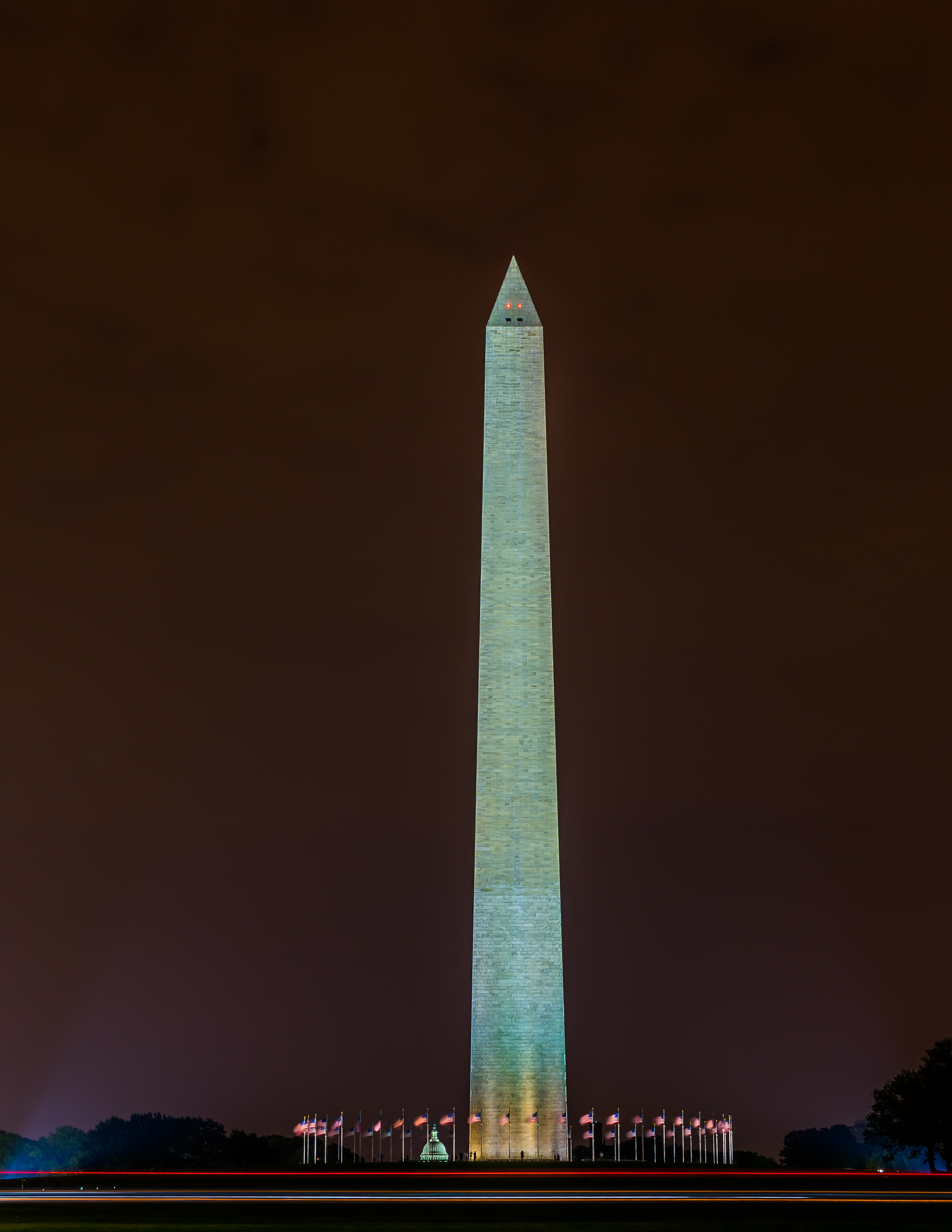 a tall monument at night with Washington Monument in the background