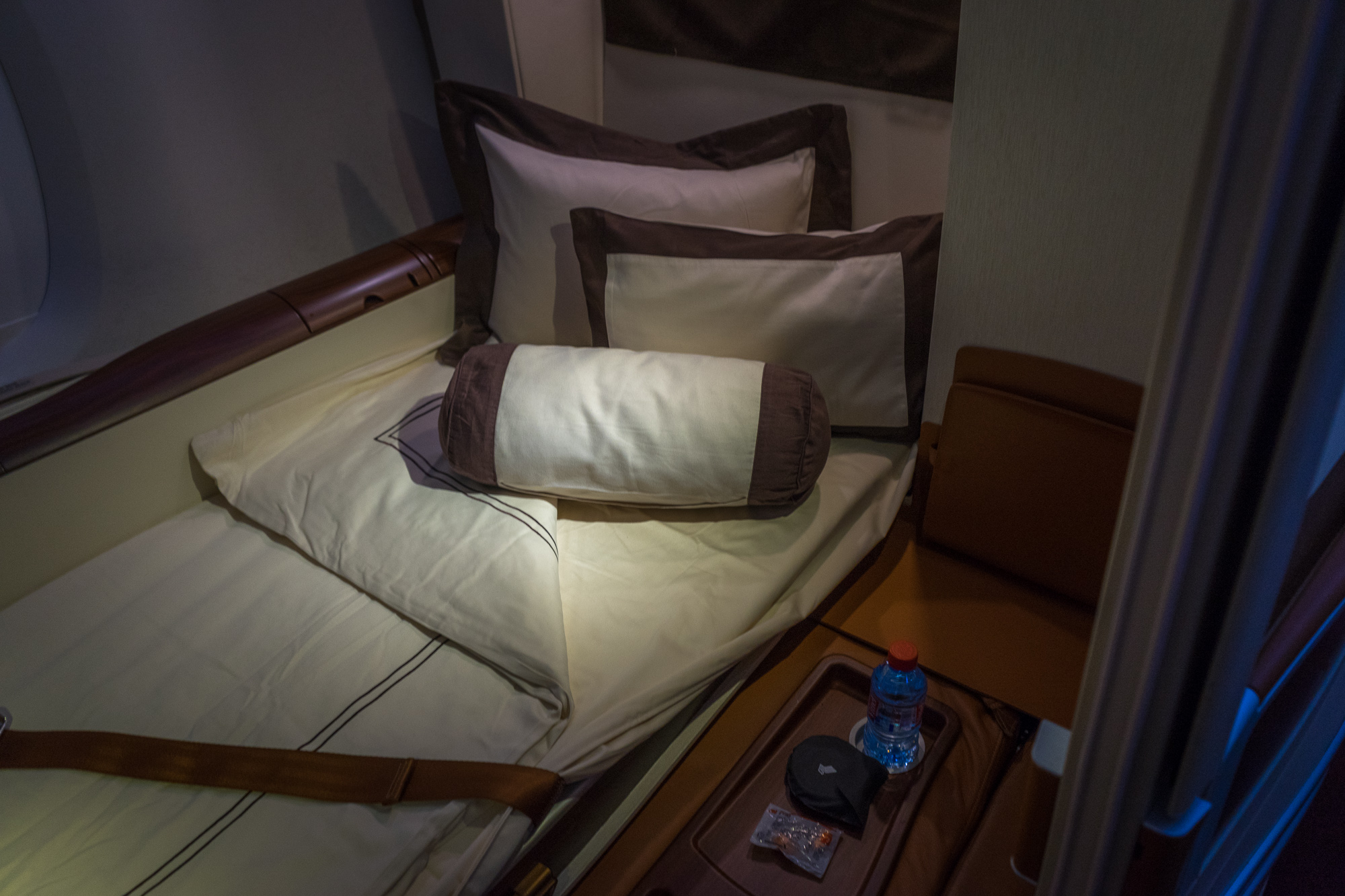 a bed with pillows and a bottle of water on a tray