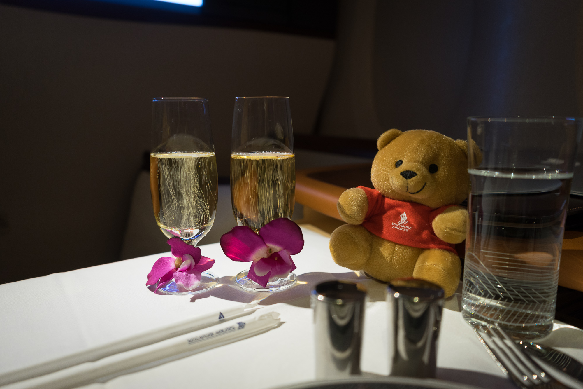 a teddy bear and two glasses of champagne on a table