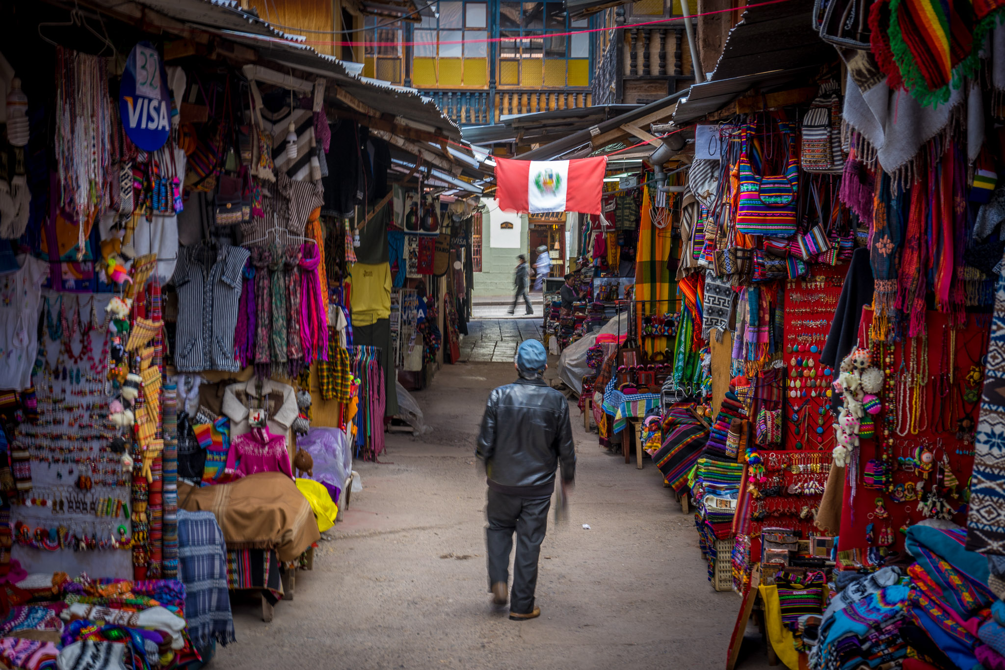 a man walking in a street with many colorful cloths