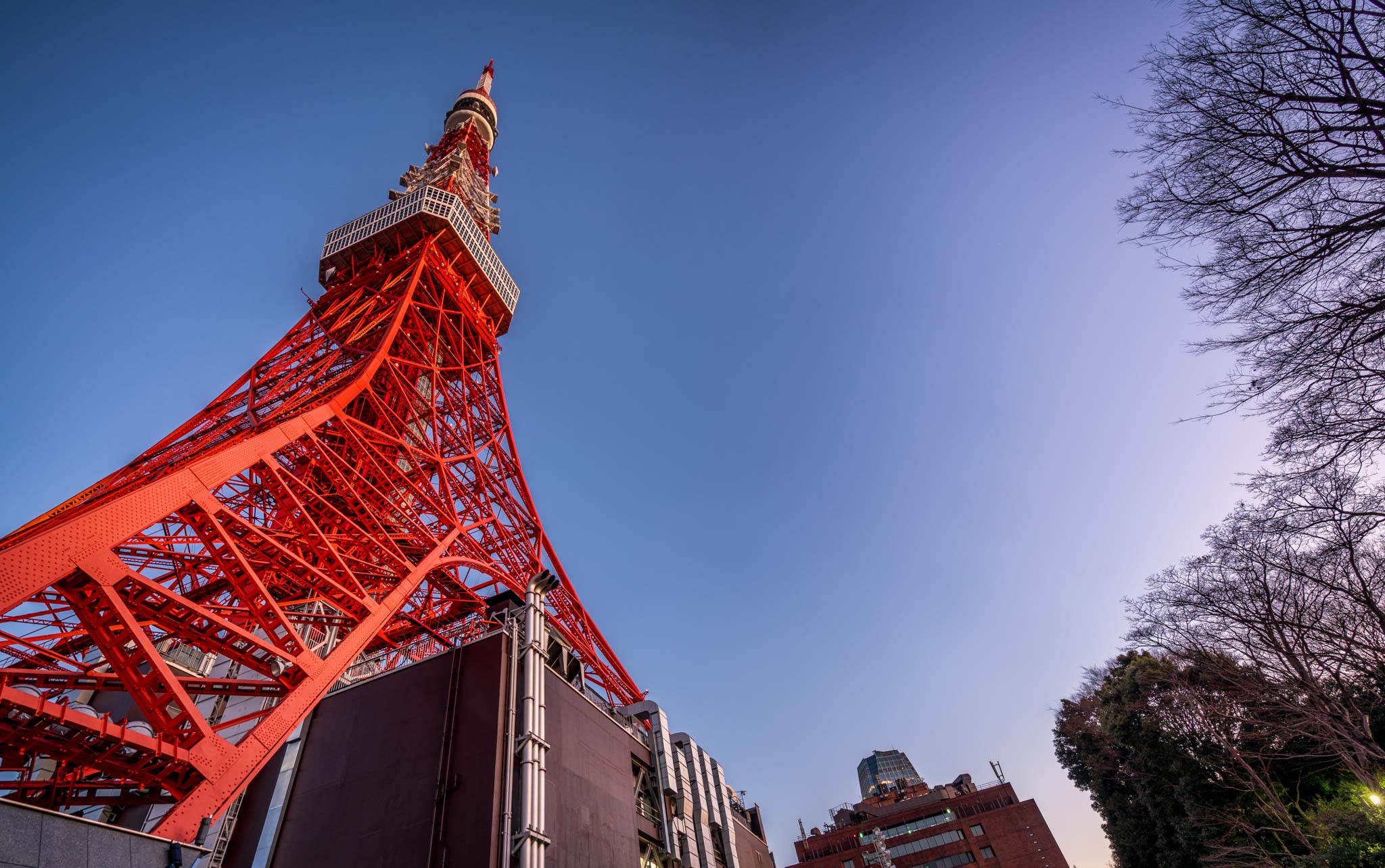 a red metal tower with a pointy top with Tokyo Tower in the background