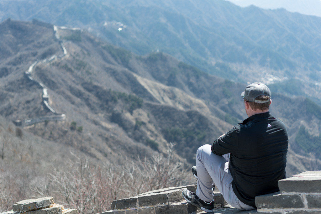 a man sitting on a wall overlooking a valley