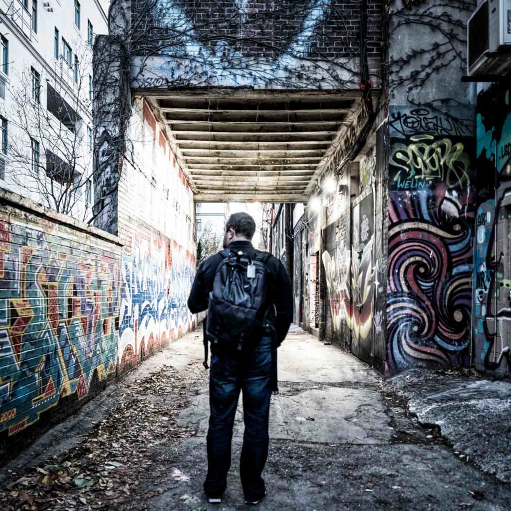 a man standing in a alley with graffiti