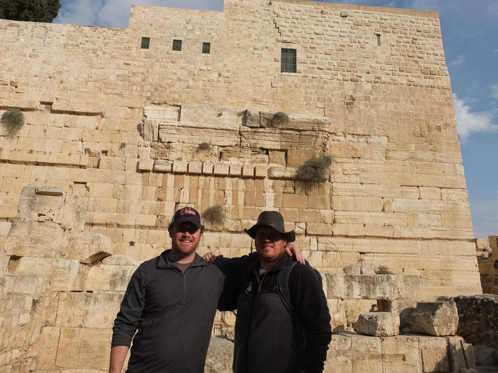 two men standing in front of a stone building with Western Wall in the background