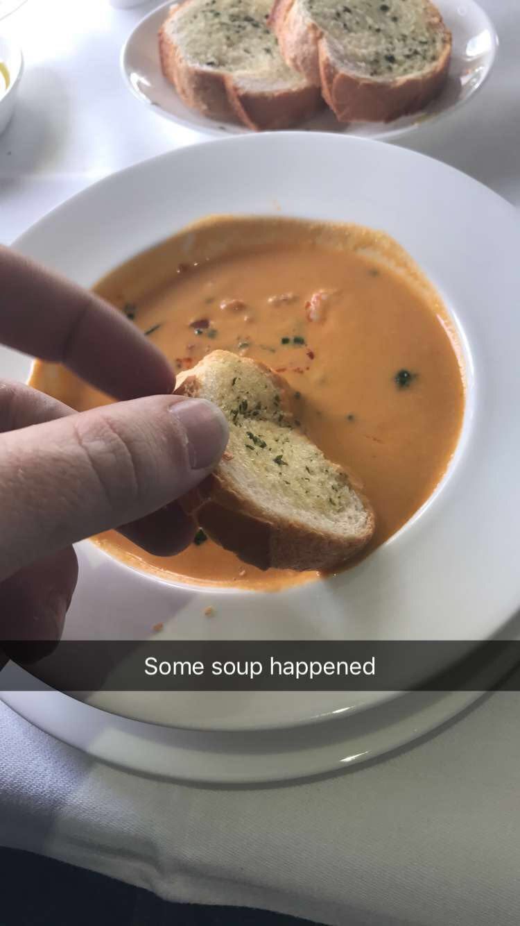 a person holding a piece of bread in a bowl of soup