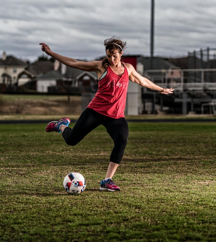 a woman kicking a football ball