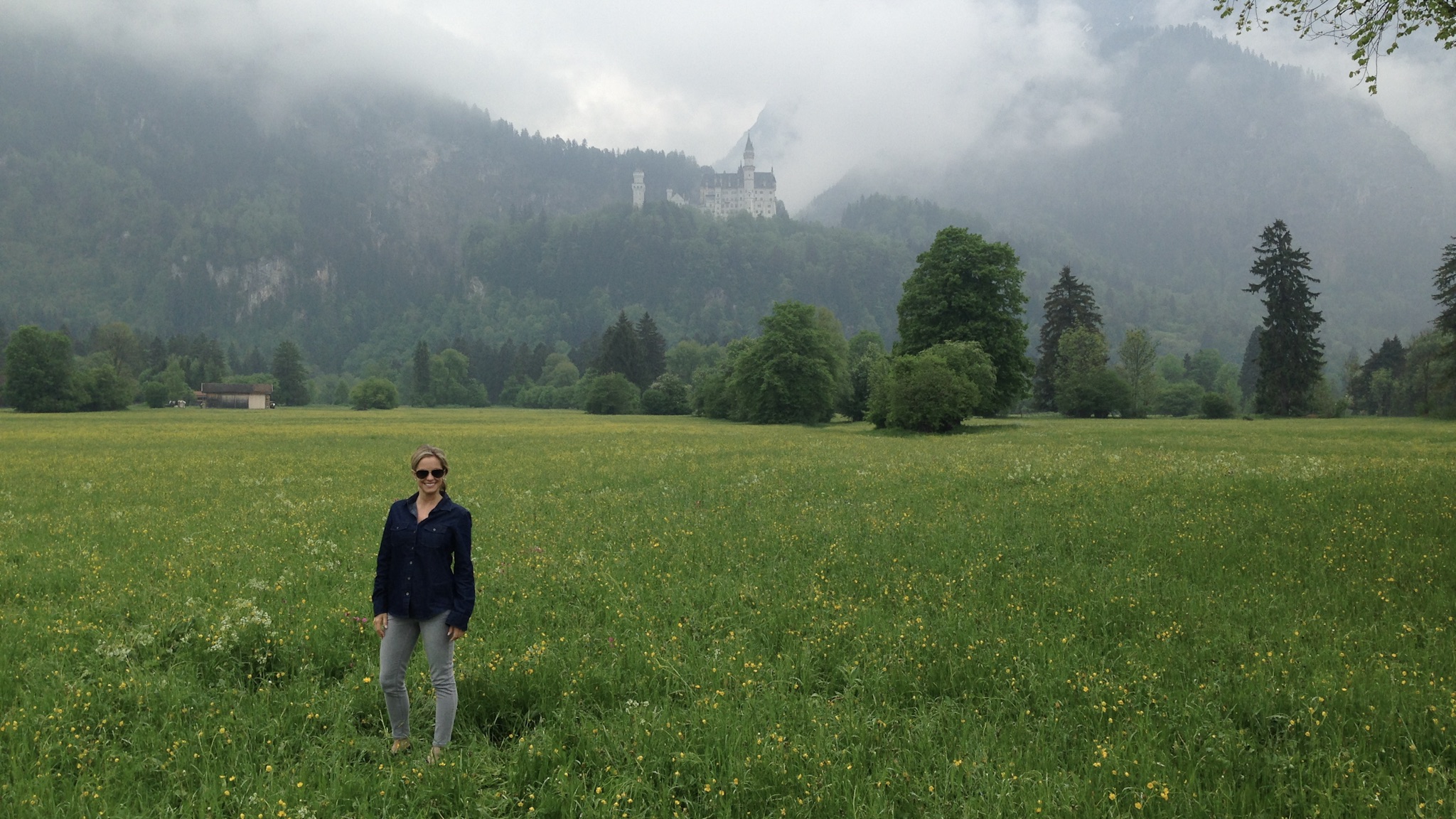 a woman standing in a field with a castle in the background