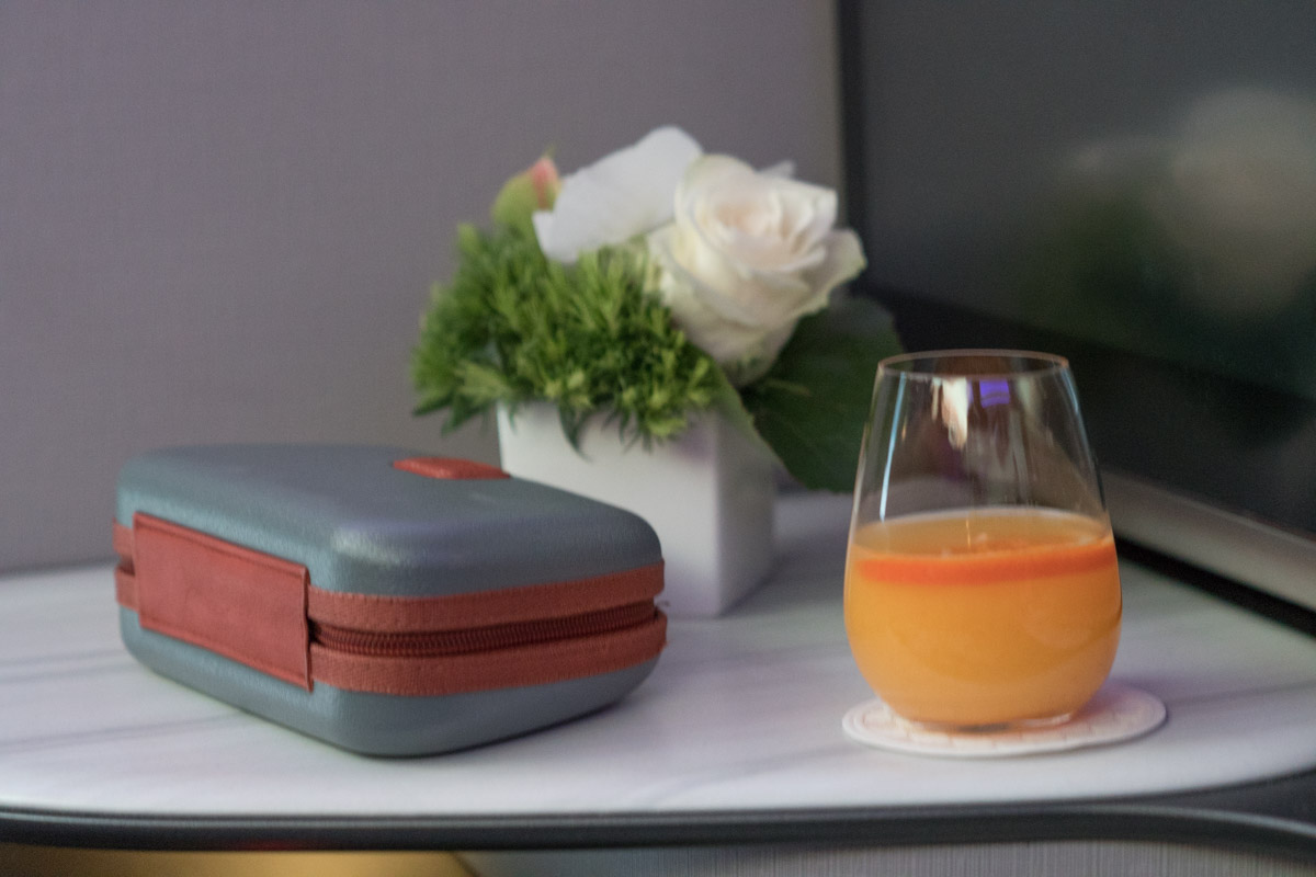 a glass of orange juice next to a case and flowers