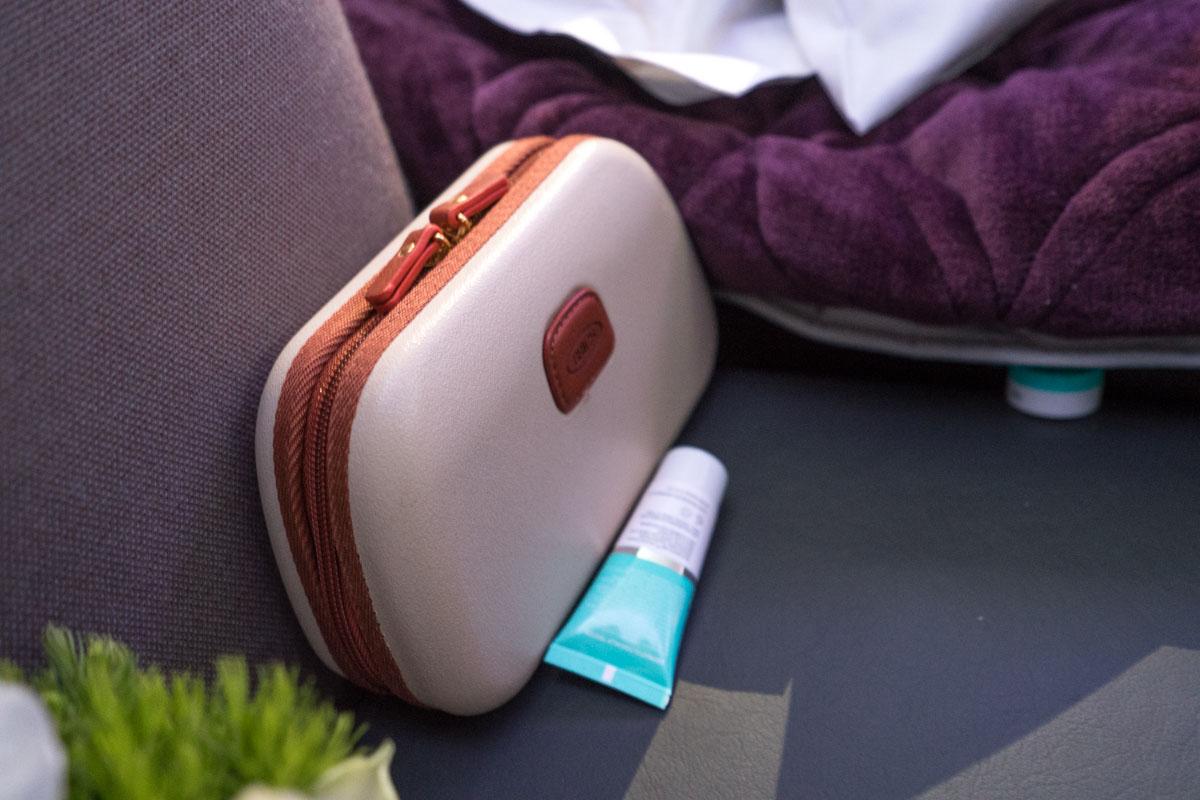 a small white and brown cosmetic bag next to a purple towel