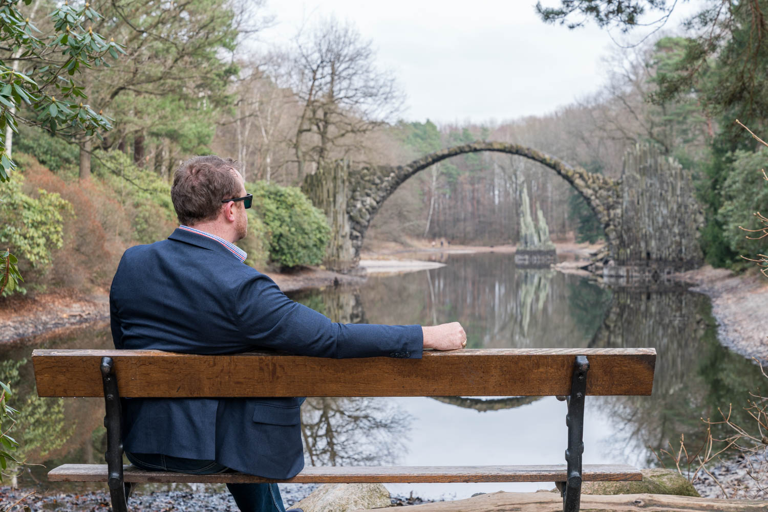 a man sitting on a bench by a lake