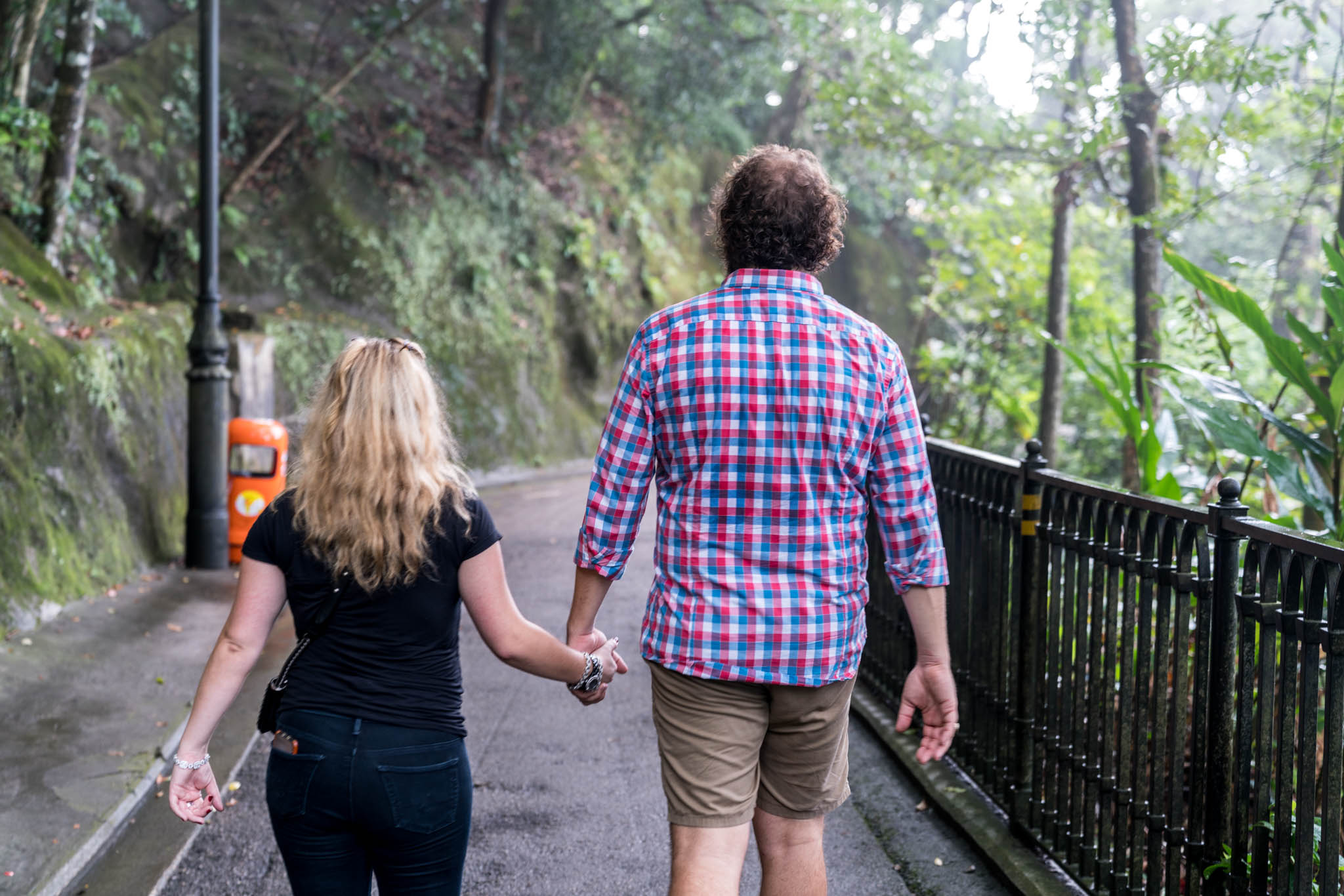 a man and woman holding hands walking down a path