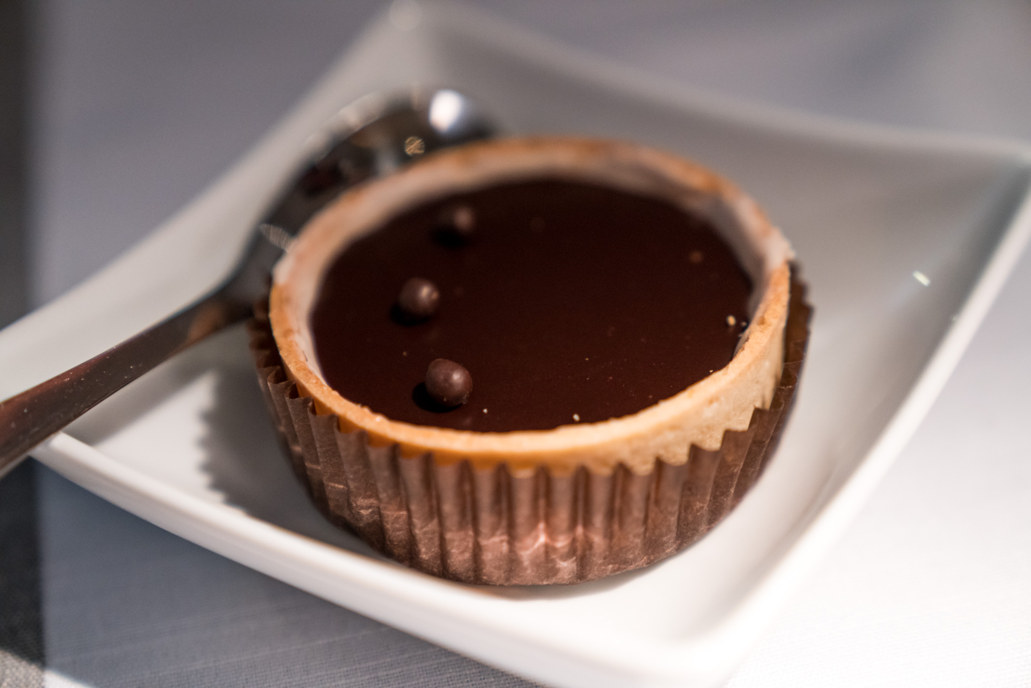 a small chocolate tart on a plate with a spoon