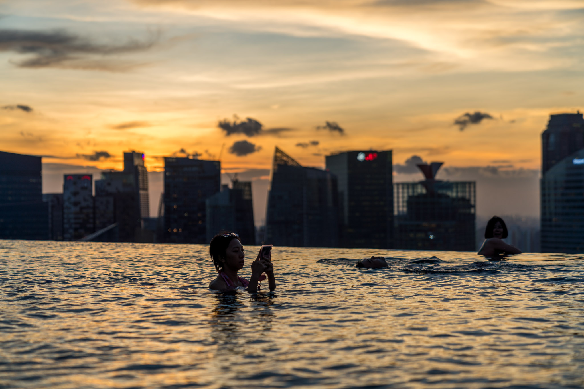 people in a pool with a city in the background