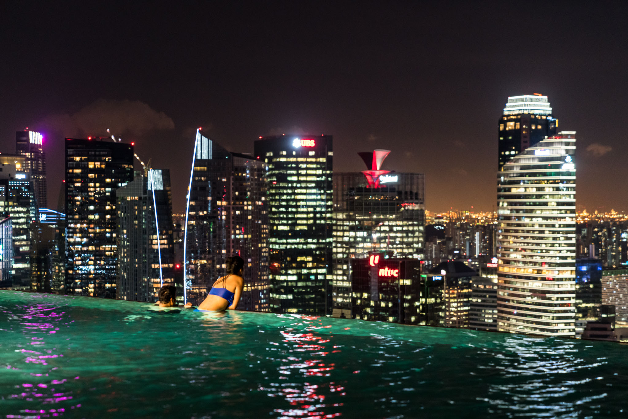 a group of people in a pool with a city in the background