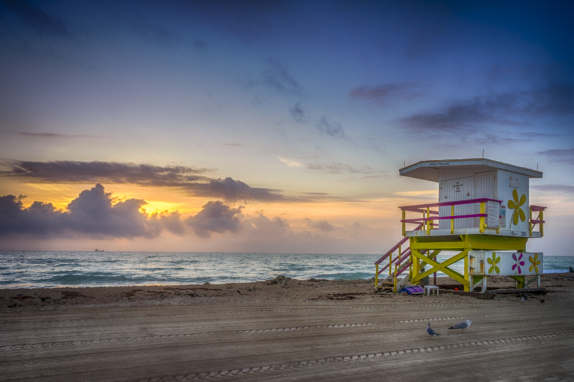 a beach with a lifeguard tower and a sunset