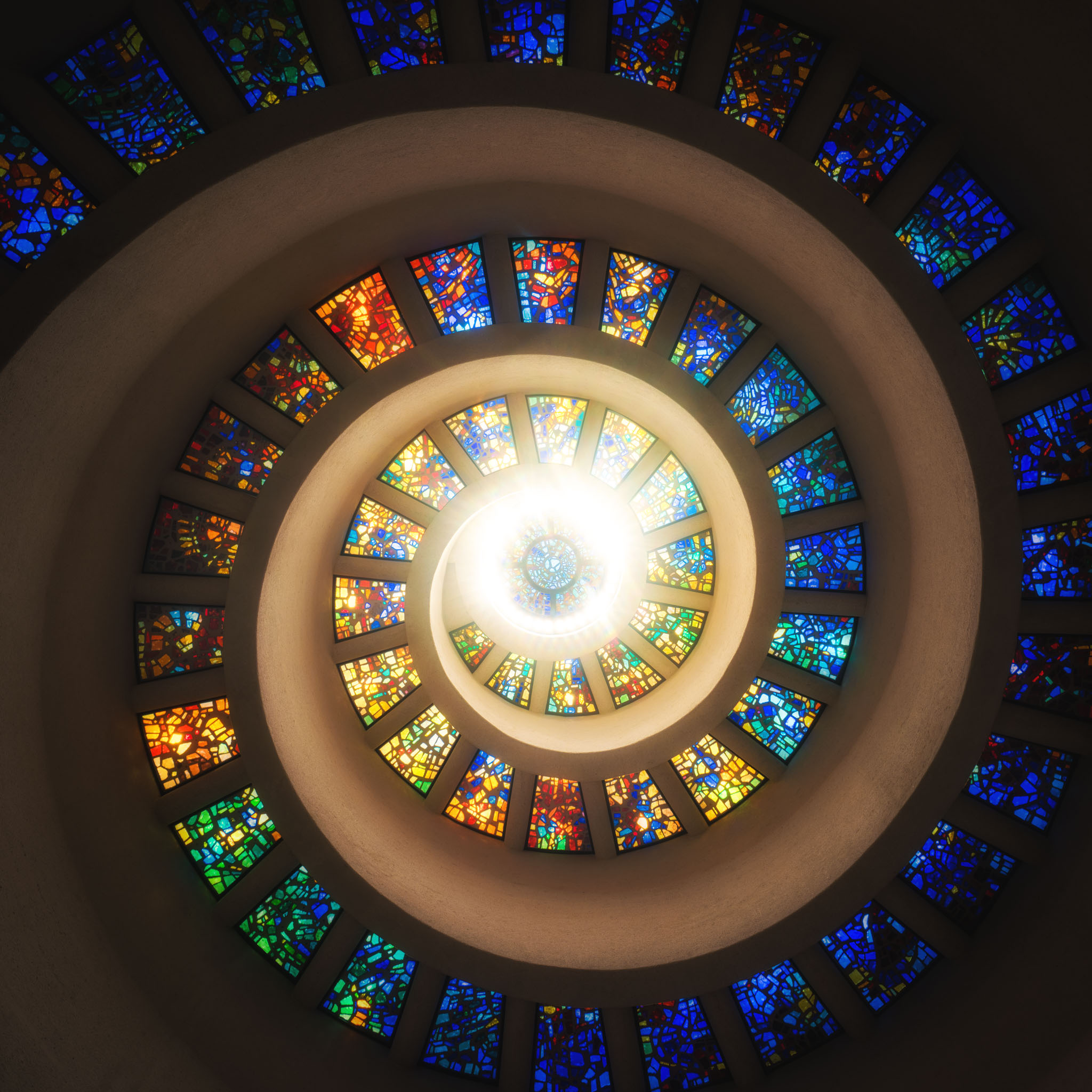 a spiral staircase with stained glass windows with Thanks-Giving Square in the background