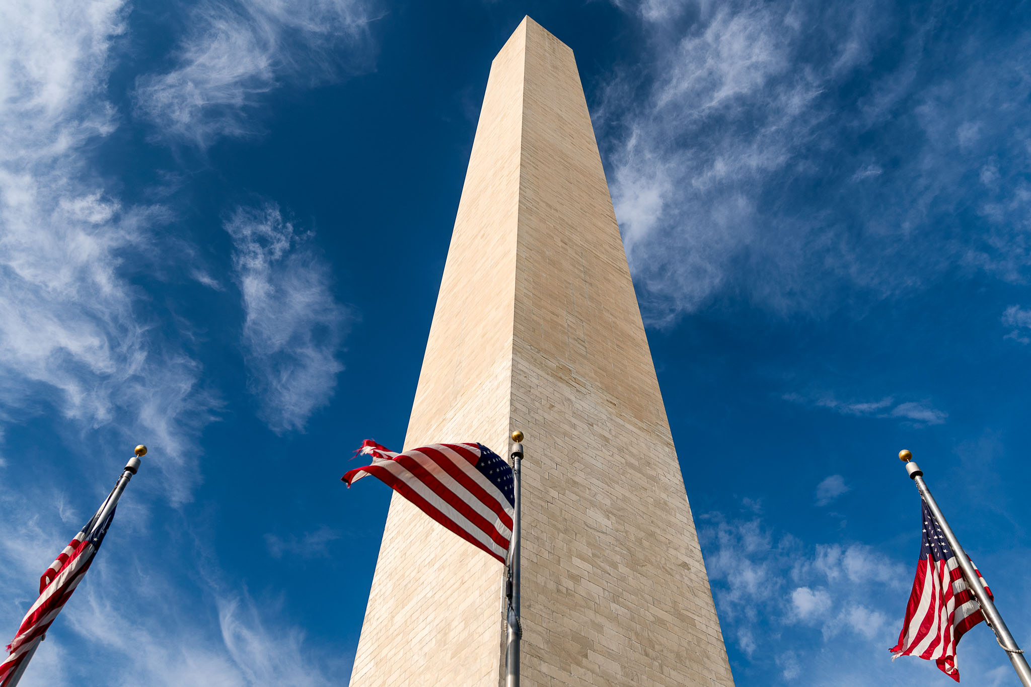a flag on a flagpole with Washington Monument in the background