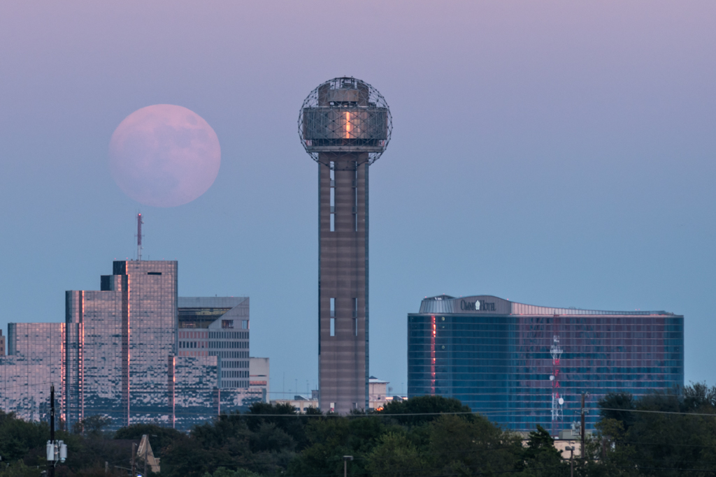a tall tower with a round ball on top and a moon in the background