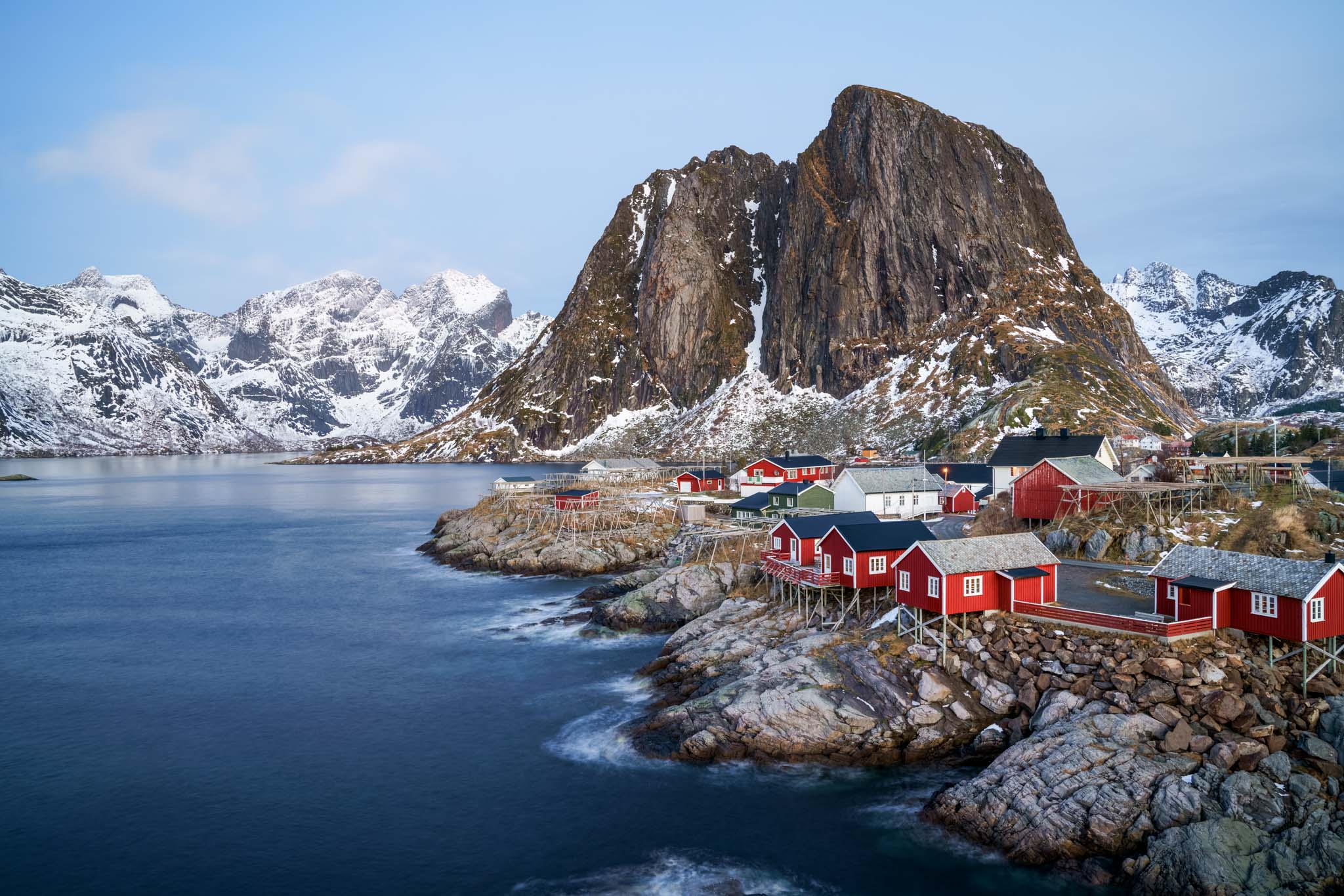 a small town on a rocky shore by a large mountain