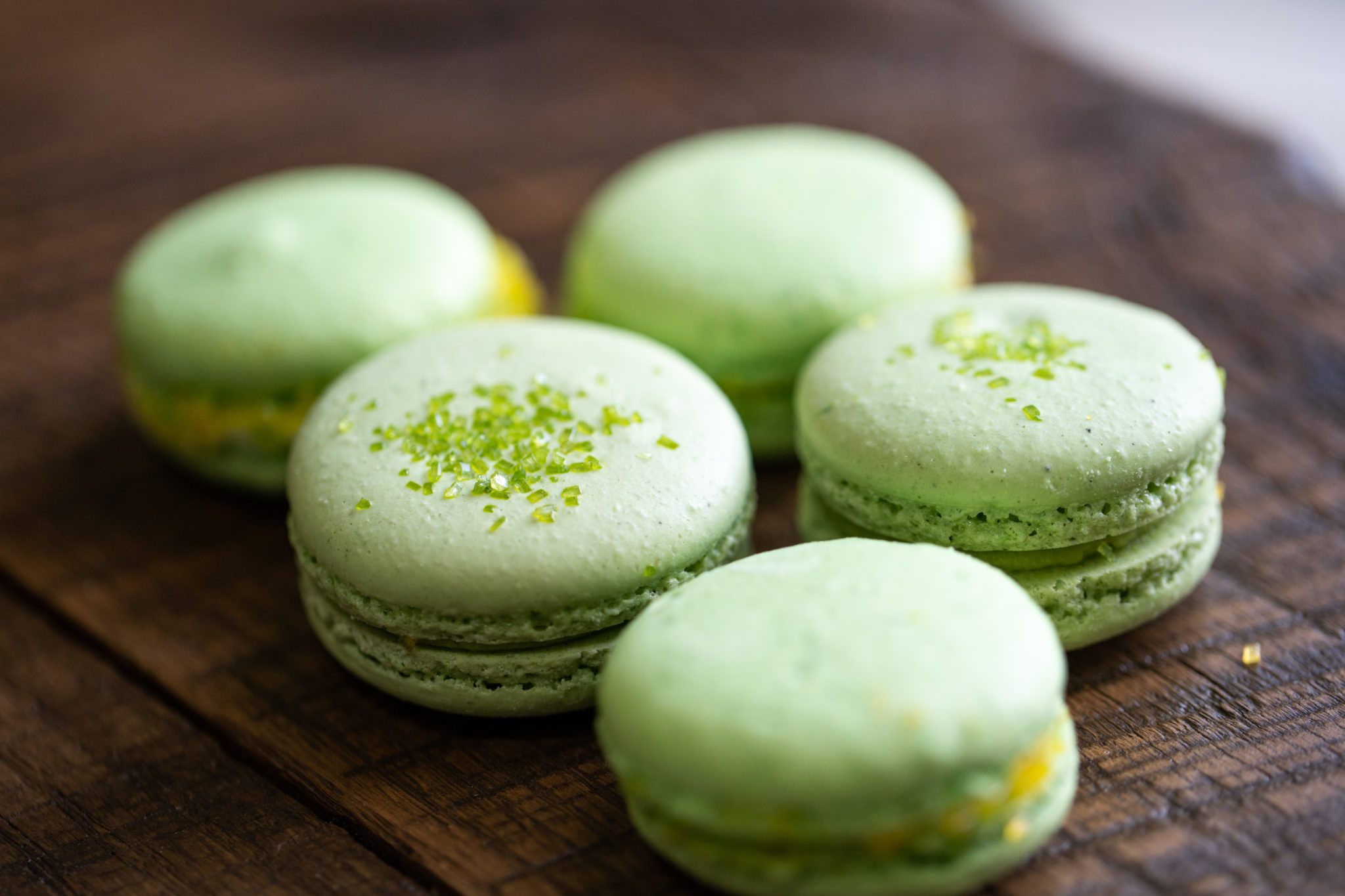 a group of green macaroons on a wood surface