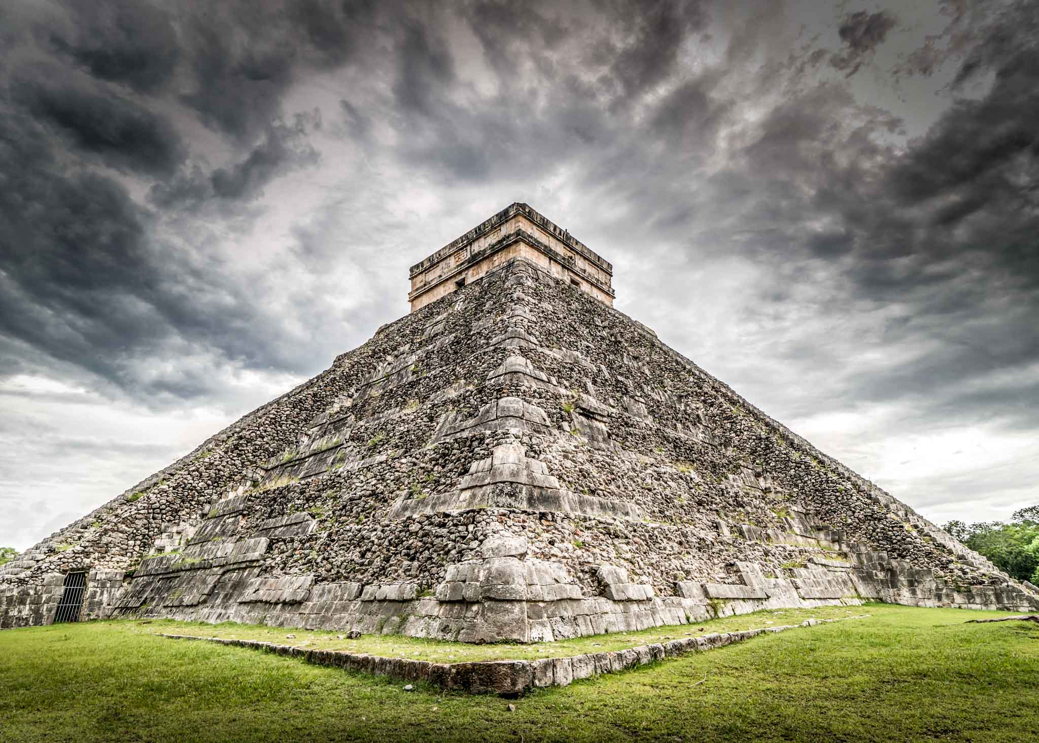a pyramid with a cloudy sky with Chichen Itza in the background