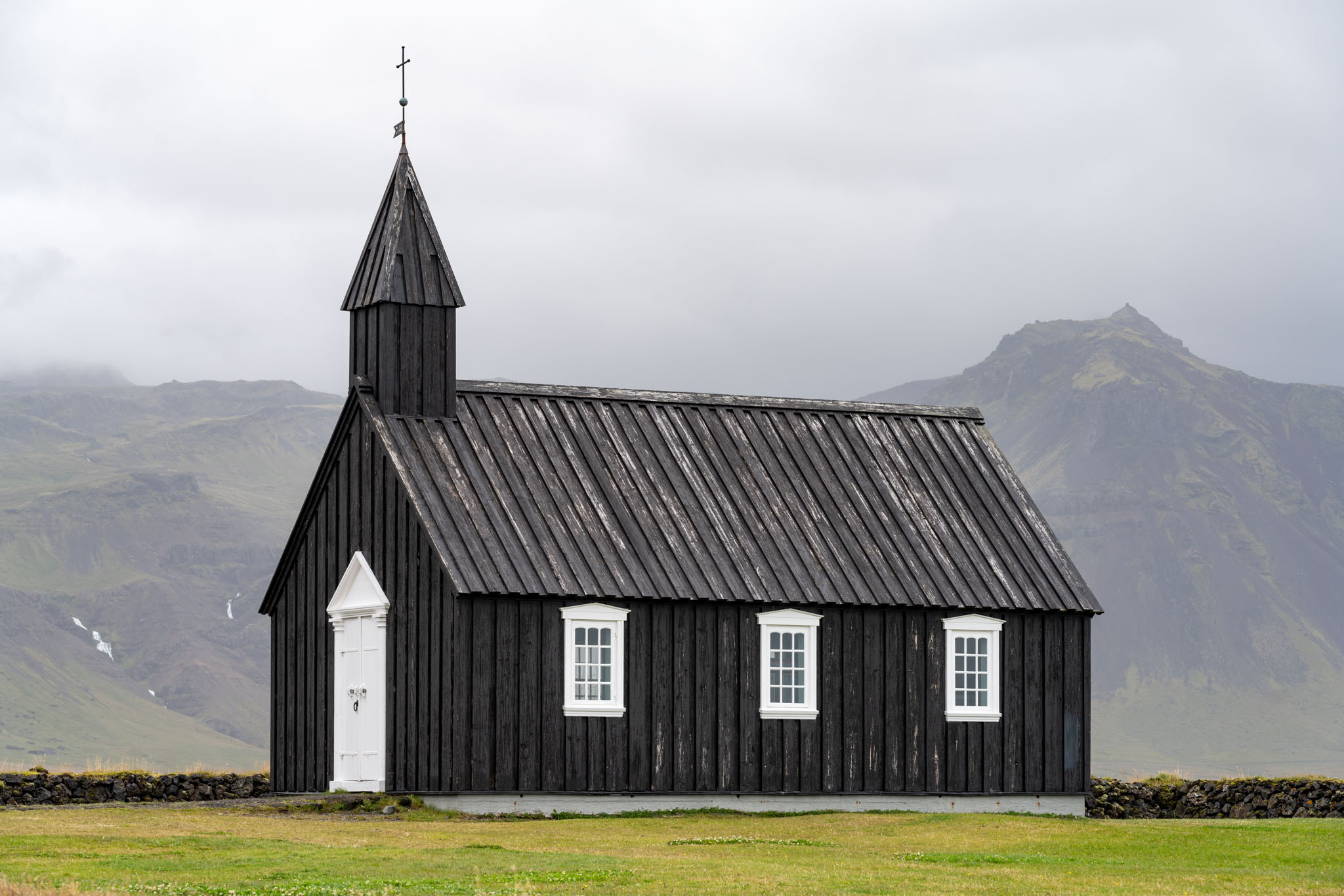a black building with a steeple and a mountain in the background