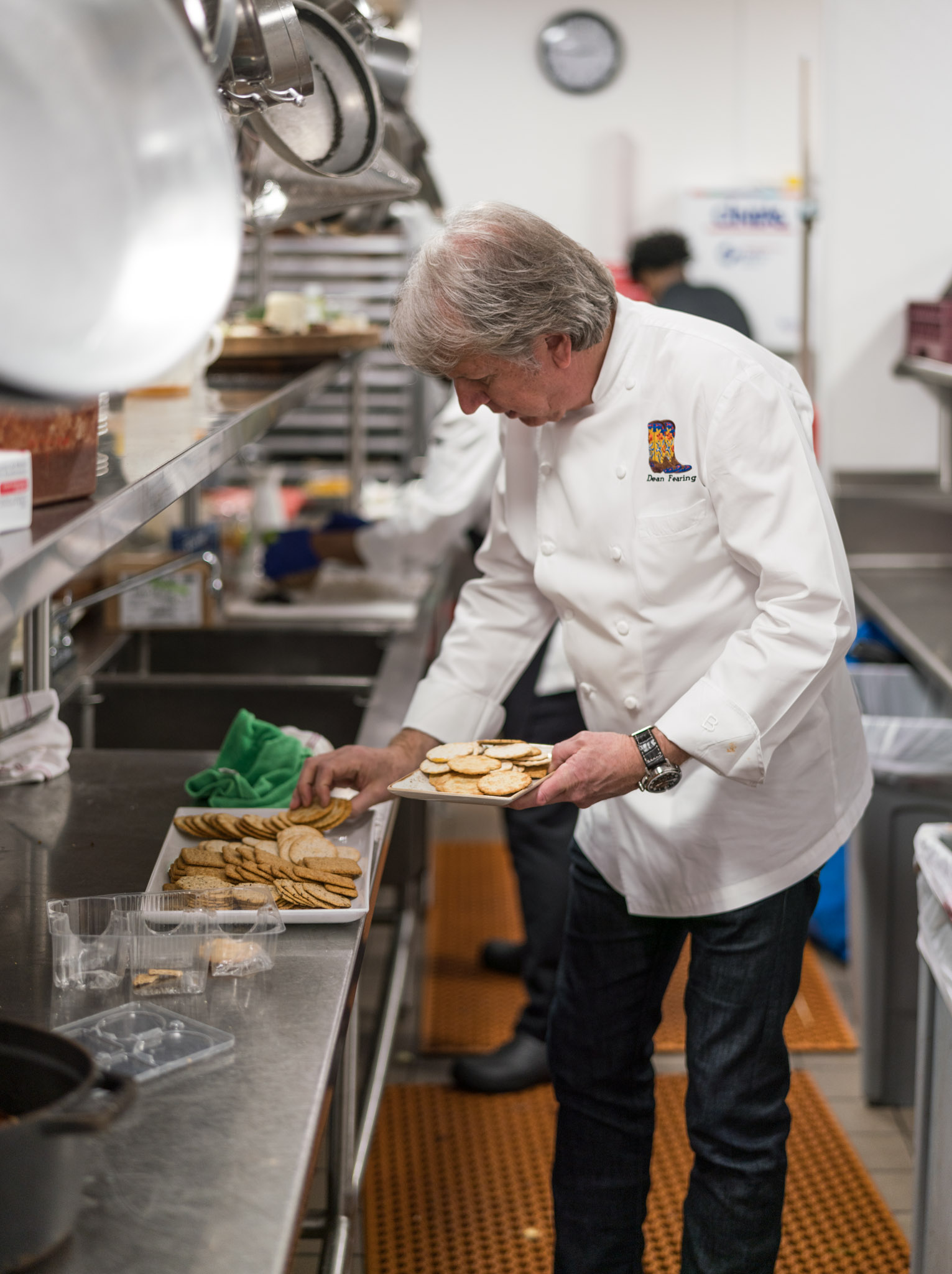 a man in a white coat holding a tray of cookies