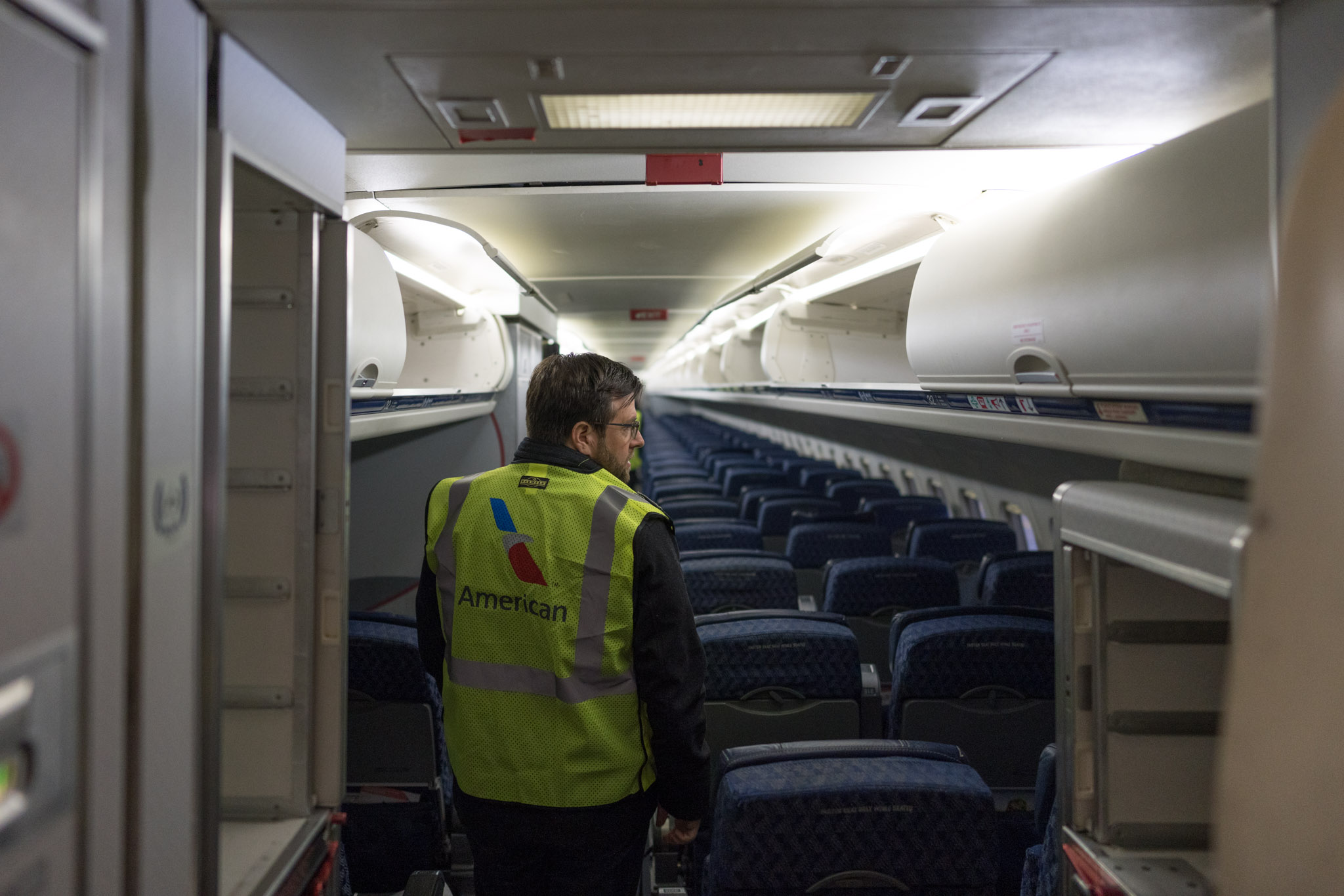 a man in a vest walking in an airplane