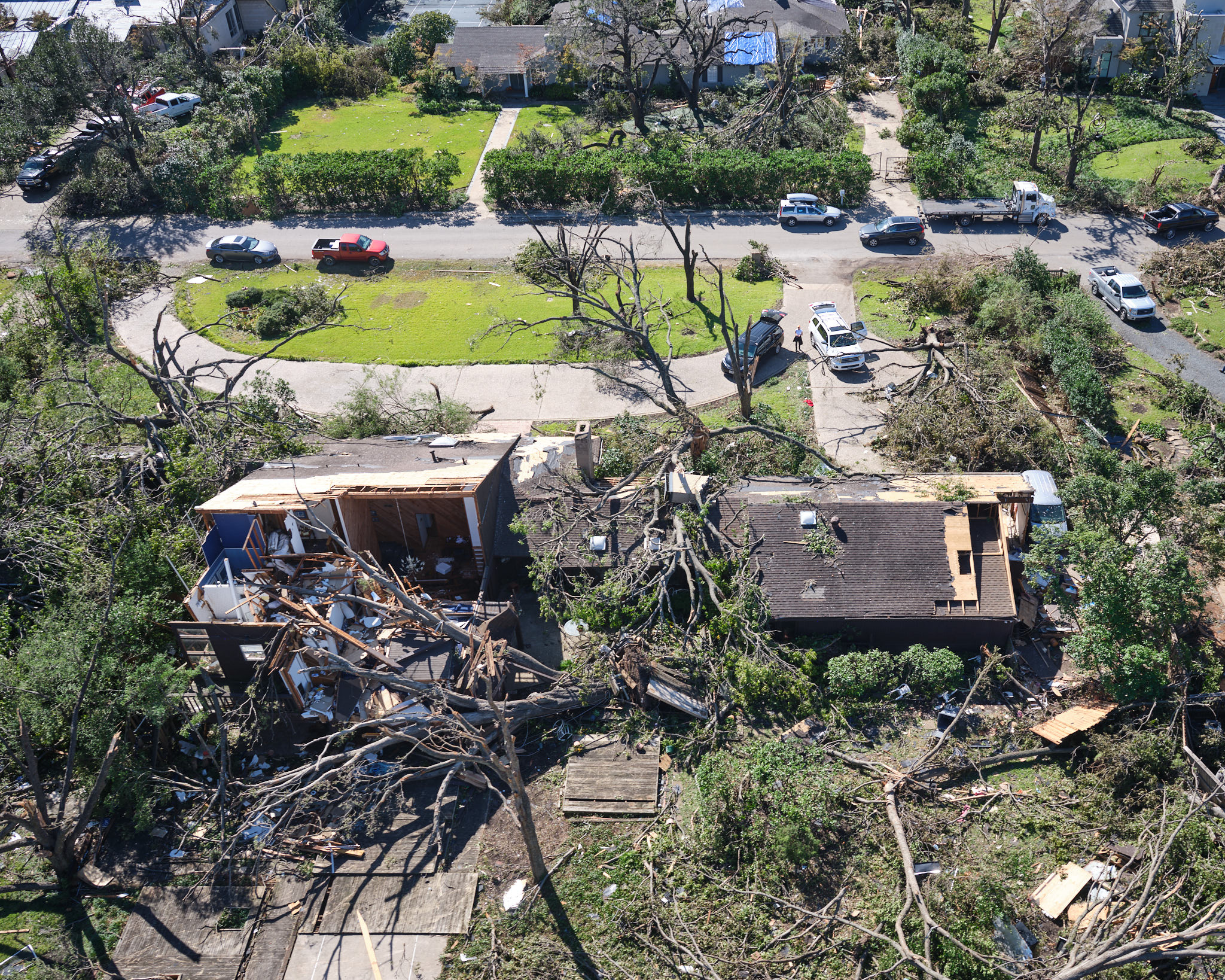 a destroyed house and cars in a neighborhood