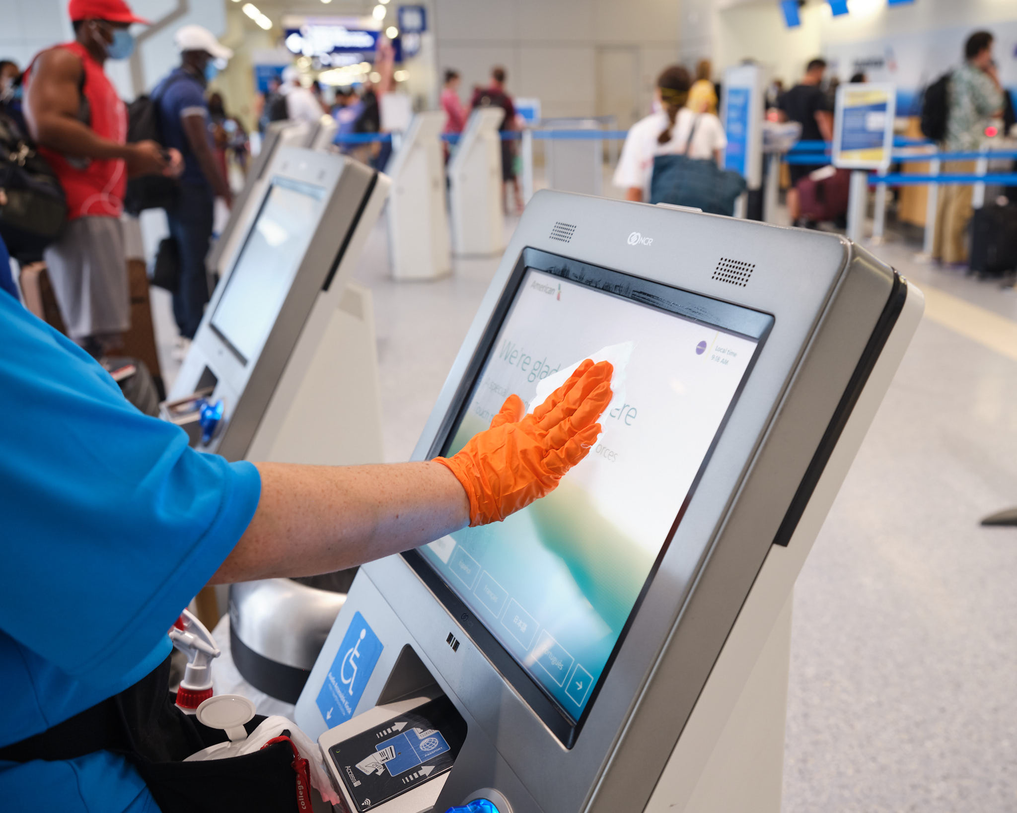 a person wearing orange gloves using a touch screen