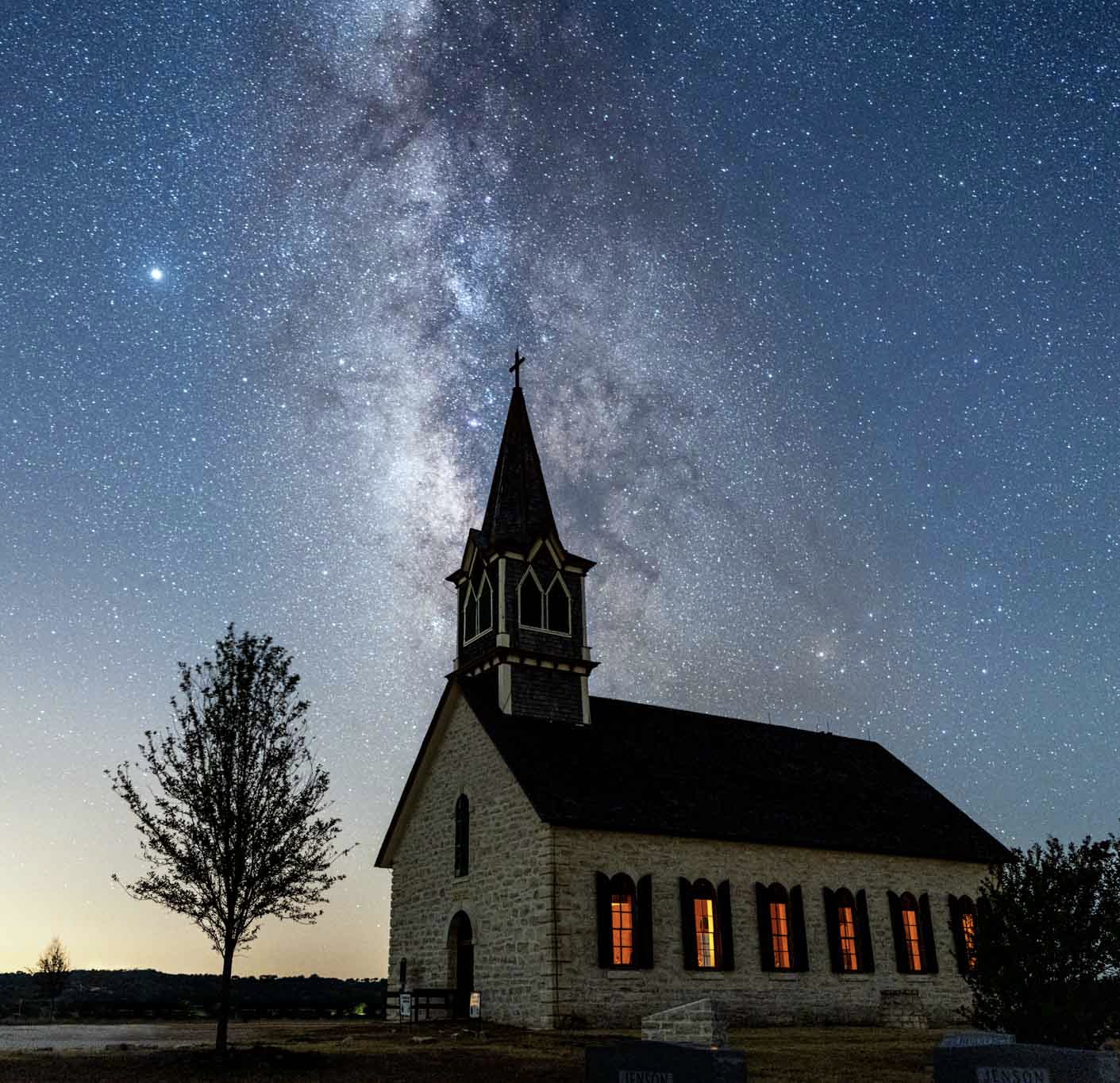 a church with a tree and stars in the sky