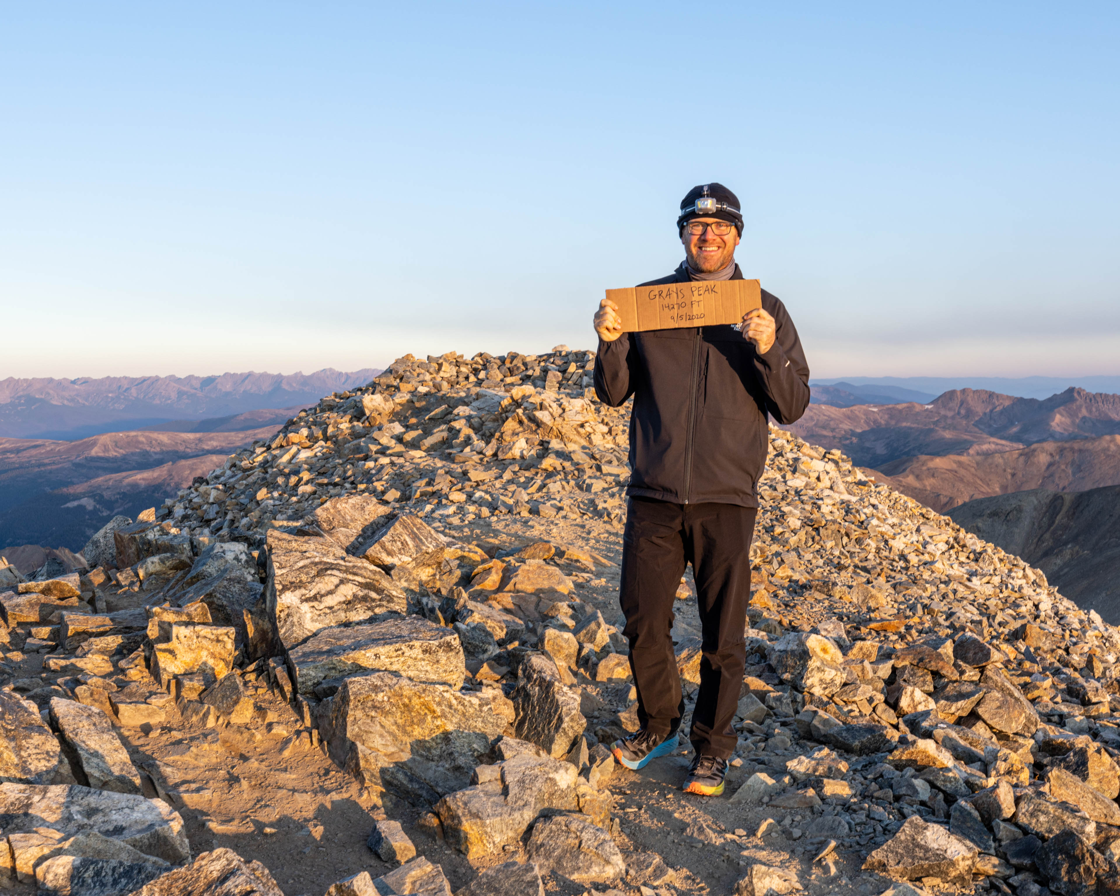 a man holding a sign on top of a mountain